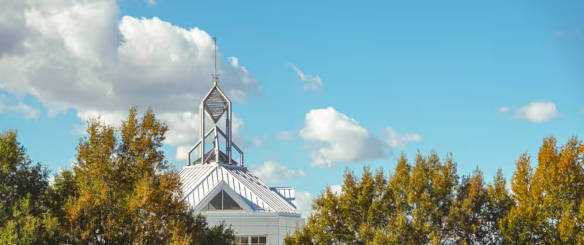 Photo of the top of the Johnson Center surrounded by green foliage